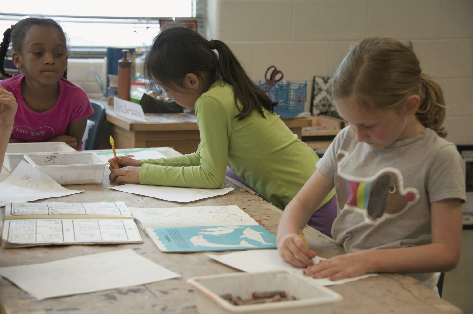 Three primary school students working at a shared table